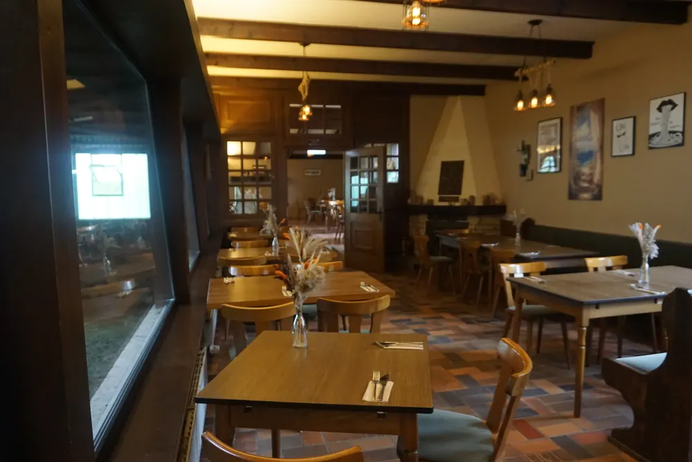 Gedeckte Holztische mit Trockenblumen im warm beleuchteten Gastraum